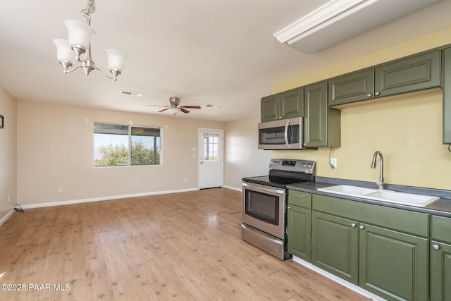 7555 W Wexford Dr, Wilhoit, AZ 86332 - kitchen with stainless steel appliances, green cabinets, a chandelier, light wood-style floors, and a ceiling fan