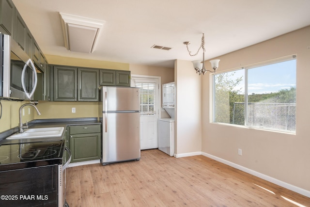 7555 W Wexford Dr, Wilhoit, AZ 86332 - kitchen featuring appliances with stainless steel finishes, stacked washer and clothes dryer, light wood-type flooring, a chandelier, and dark countertops