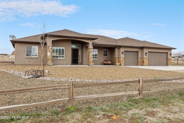 view of front facade with fence, an attached garage, stucco siding, and concrete driveway
