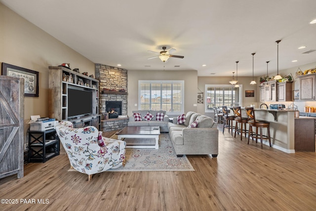 living room with wood finished floors, a ceiling fan, a fireplace, and recessed lighting