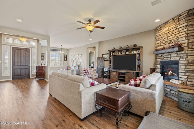 living room featuring wood finished floors, a ceiling fan, a stone fireplace, baseboards, and recessed lighting