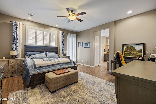 bedroom featuring wood finished floors, ensuite bath, recessed lighting, baseboards, and an office area