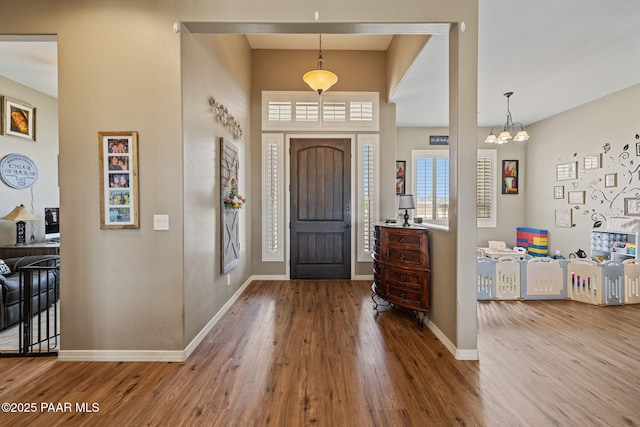 foyer entrance featuring wood finished floors, baseboards, and a chandelier
