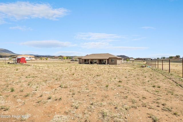view of yard featuring fence, a view of rural / pastoral area, an outdoor structure, and a storage unit