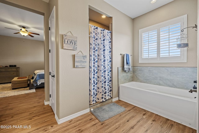 ensuite bathroom featuring wood finished floors, a ceiling fan, a shower with shower curtain, and a garden tub