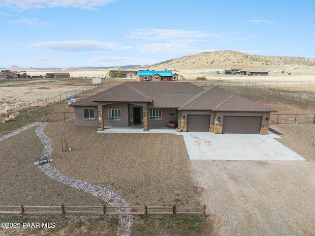 view of front of house with driveway, a garage, a mountain view, and fence