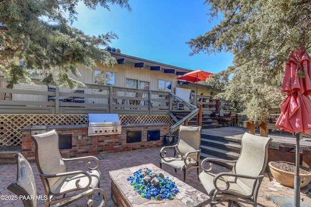 view of patio featuring exterior kitchen, a grill, and a wooden deck