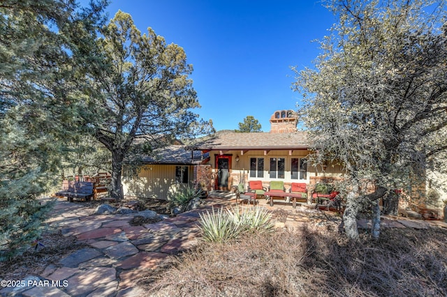 view of front of home with a patio area, a chimney, and an outdoor hangout area