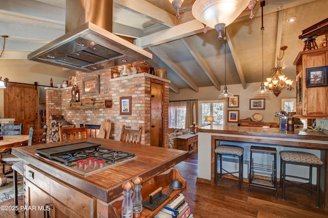 kitchen featuring vaulted ceiling with beams, a barn door, island range hood, stainless steel gas cooktop, and dark wood-style floors