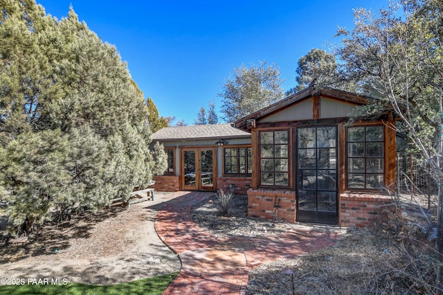 back of property with french doors and brick siding