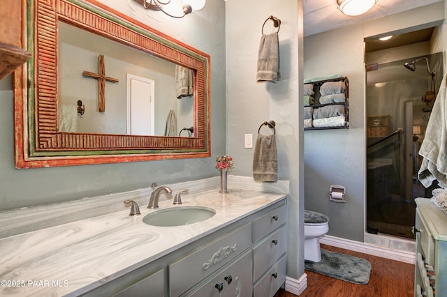 full bathroom featuring toilet, a shower stall, vanity, wood finished floors, and baseboards