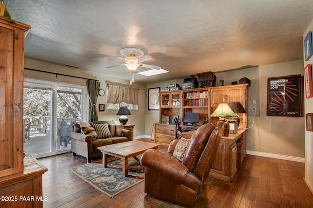 living area featuring a skylight, baseboards, and hardwood / wood-style floors