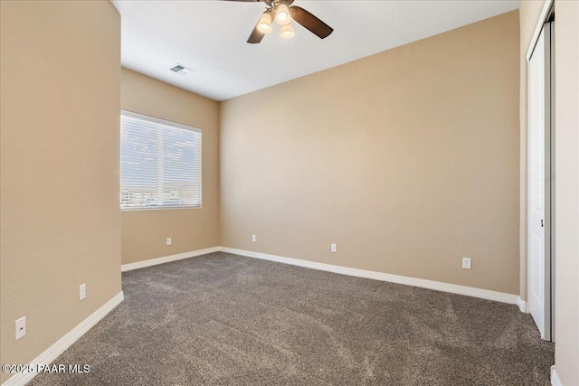 unfurnished bedroom featuring dark colored carpet, visible vents, baseboards, and ceiling fan