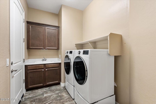 clothes washing area featuring washer and clothes dryer, cabinet space, and a sink