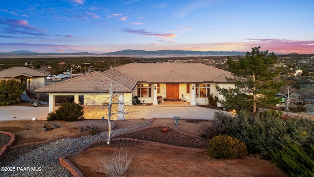 view of front of property featuring a patio area, a tile roof, a mountain view, and stucco siding