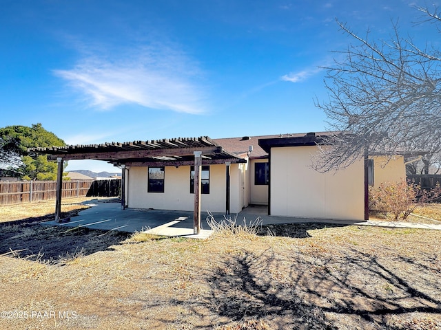 view of front of house featuring fence, a patio area, a pergola, and stucco siding