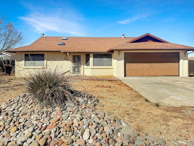 ranch-style home with stucco siding, fence, roof with shingles, concrete driveway, and a garage