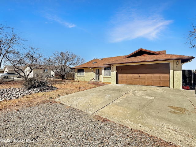 single story home with stucco siding, a garage, driveway, and fence