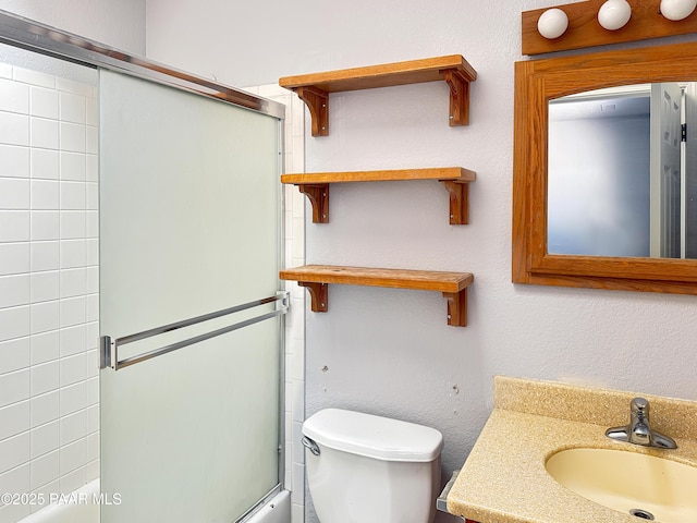 full bath featuring combined bath / shower with glass door, toilet, vanity, and a textured wall