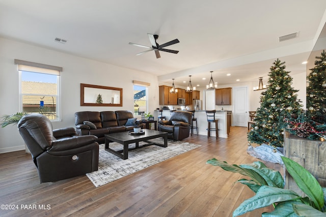 living room with light hardwood / wood-style flooring and ceiling fan with notable chandelier