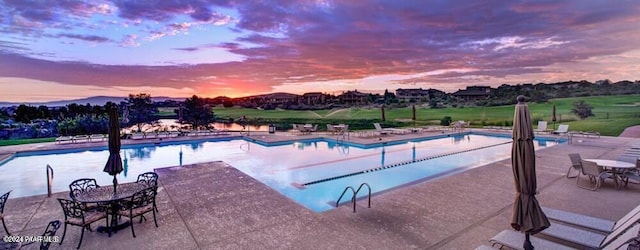 pool at dusk featuring a patio area