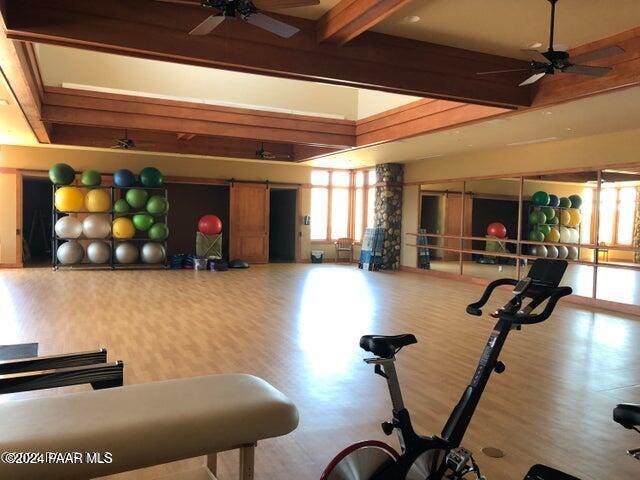 exercise room featuring a barn door, hardwood / wood-style flooring, and ceiling fan