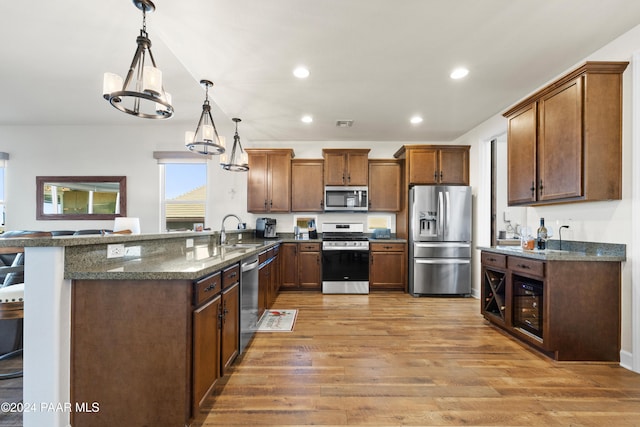 kitchen featuring stainless steel appliances, kitchen peninsula, hardwood / wood-style floors, a chandelier, and pendant lighting