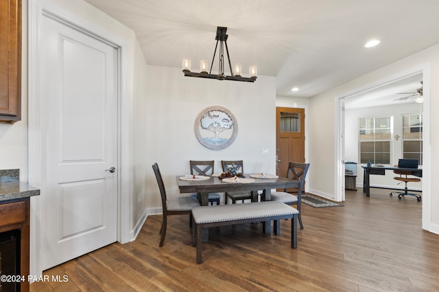 dining space with hardwood / wood-style floors and ceiling fan with notable chandelier