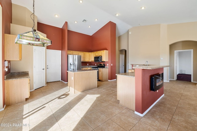 kitchen featuring light brown cabinets, high vaulted ceiling, a center island with sink, light tile patterned floors, and appliances with stainless steel finishes