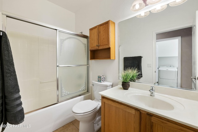 full bathroom featuring vanity, shower / bath combination with glass door, tile patterned floors, toilet, and washer / dryer