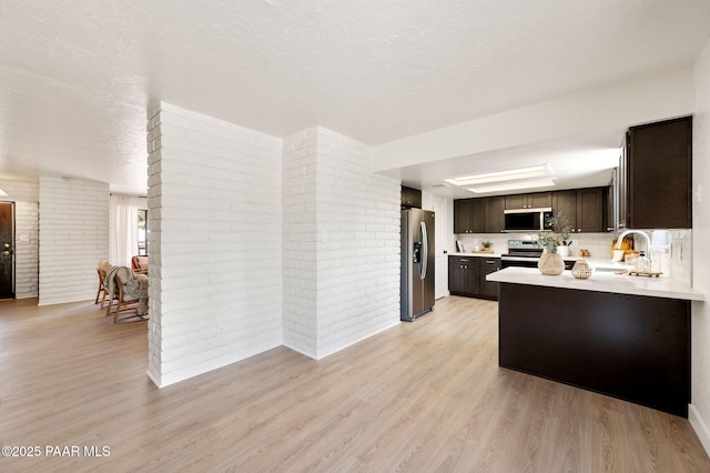 679 Tawa Ct, Prescott, AZ 86301 - kitchen featuring appliances with stainless steel finishes, brick wall, dark brown cabinets, light countertops, and light wood-style floors