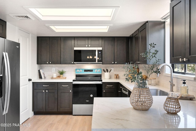 679 Tawa Ct, Prescott, AZ 86301 - kitchen with stainless steel appliances, a sink, decorative backsplash, light wood-style flooring, and light stone counters