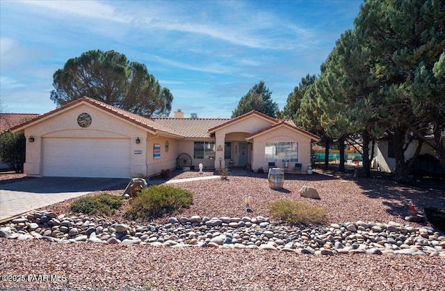 view of front of property with an attached garage, a tile roof, decorative driveway, stucco siding, and a chimney