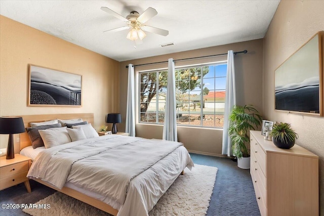 carpeted bedroom featuring a textured ceiling, visible vents, and ceiling fan