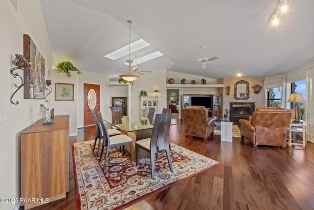 2751 Boone Ct, Prescott, AZ 86305 - dining room featuring a ceiling fan, vaulted ceiling, a skylight, dark wood-style flooring, and a large fireplace