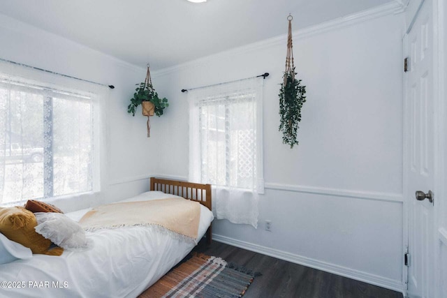 bedroom featuring dark wood finished floors, crown molding, and baseboards