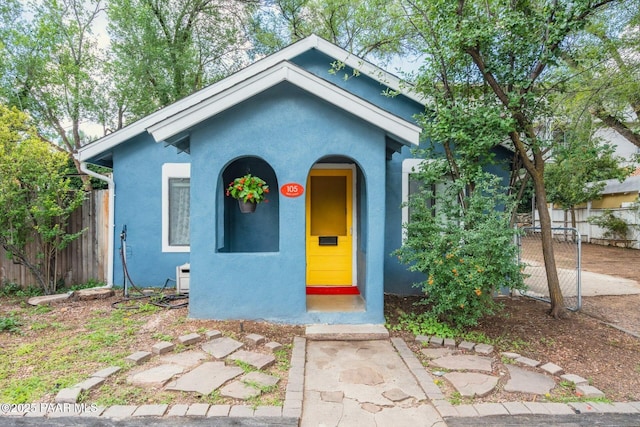 view of front facade with fence and stucco siding