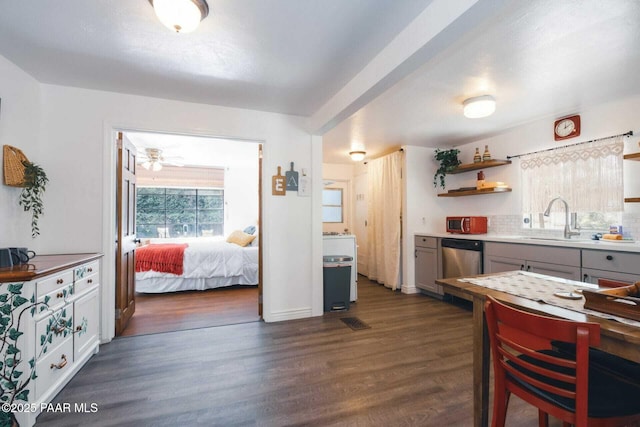 kitchen with a sink, gray cabinetry, dark wood-type flooring, decorative backsplash, and stainless steel dishwasher