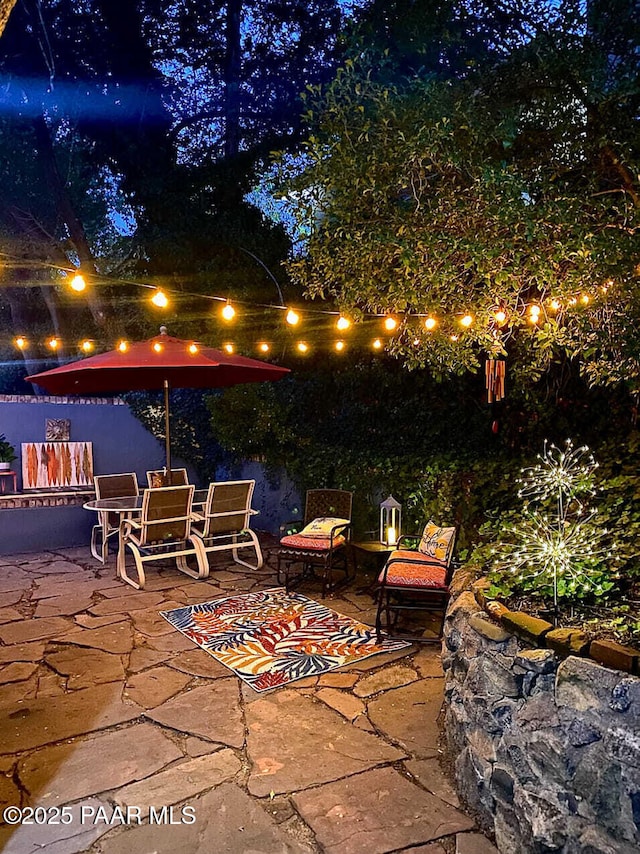 patio at twilight with outdoor dining area and fence