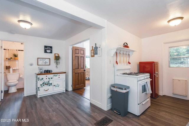 kitchen featuring visible vents, baseboards, white range with gas stovetop, and dark wood-style flooring