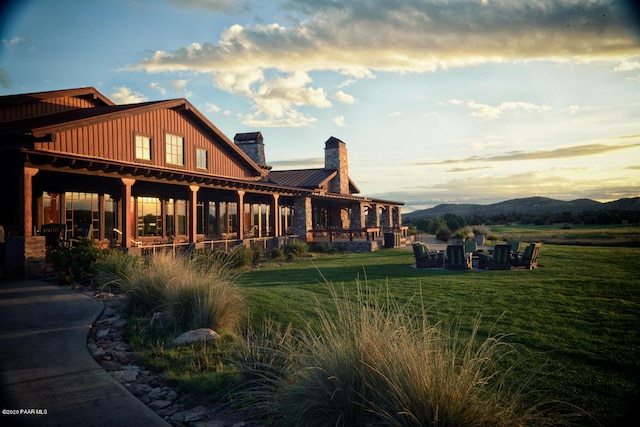 back house at dusk with a mountain view and a yard