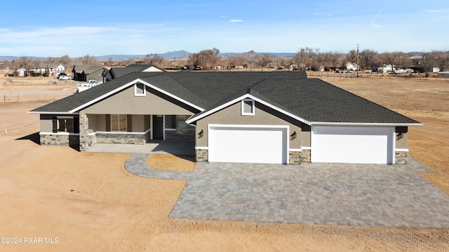 craftsman inspired home with stucco siding, covered porch, decorative driveway, stone siding, and a garage