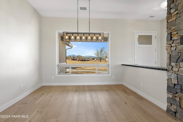 unfurnished dining area featuring hardwood / wood-style flooring, baseboards, and visible vents