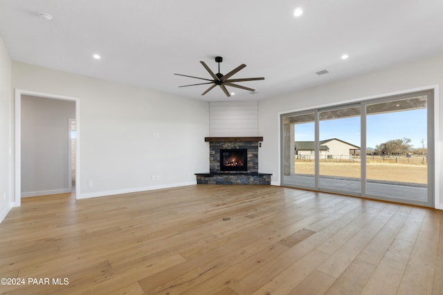 unfurnished living room featuring light wood-type flooring, visible vents, recessed lighting, a ceiling fan, and a stone fireplace