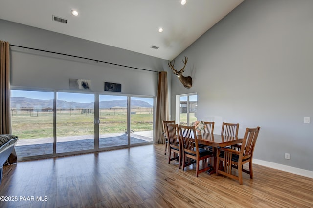 dining space with high vaulted ceiling, wood finished floors, a mountain view, recessed lighting, and baseboards