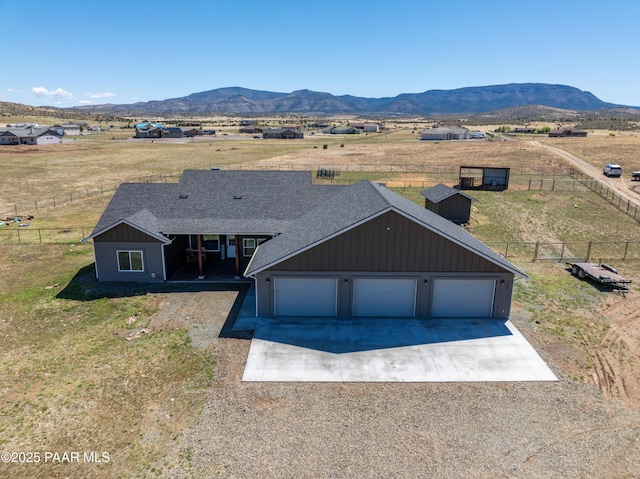 view of front of property with driveway, a mountain view, board and batten siding, a shingled roof, and a garage