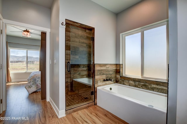 ensuite bathroom featuring wood finished floors, a stall shower, a bath, and ceiling fan