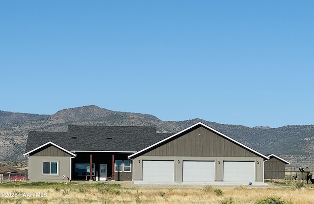 view of front of home with a mountain view, a garage, a shingled roof, and driveway
