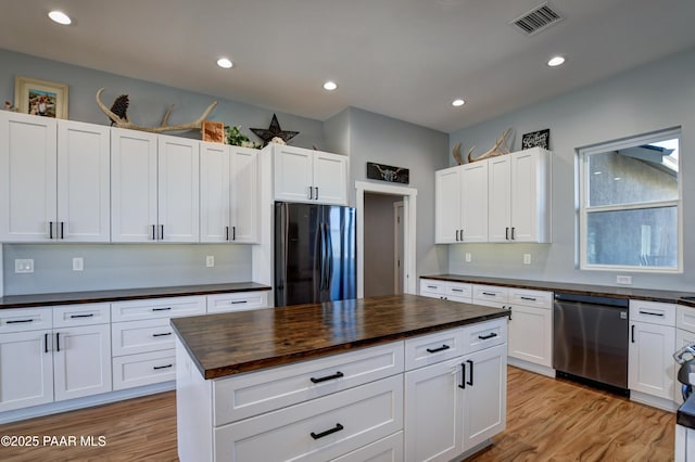 kitchen with freestanding refrigerator, stainless steel dishwasher, wooden counters, light wood-type flooring, and white cabinets