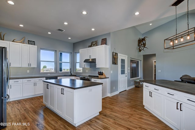 kitchen featuring black range with electric cooktop, under cabinet range hood, a kitchen island, white cabinetry, and recessed lighting